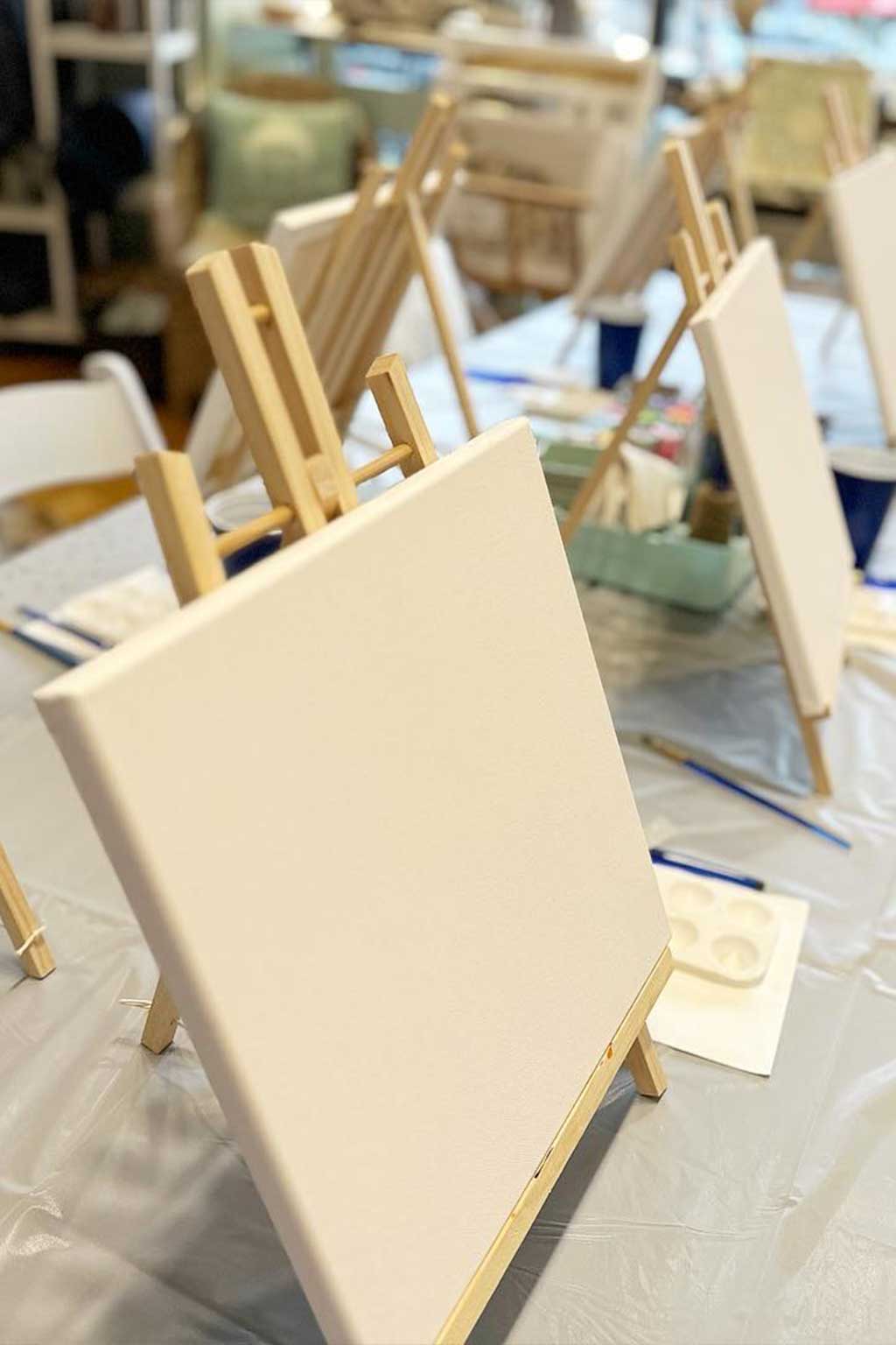 Blank canvas on an easel with art supplies in a classroom setting