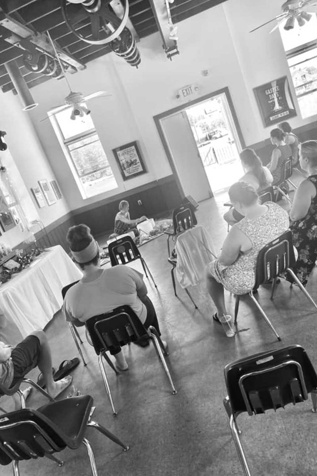 Black and white interior of an event hall with patrons seated at tables.