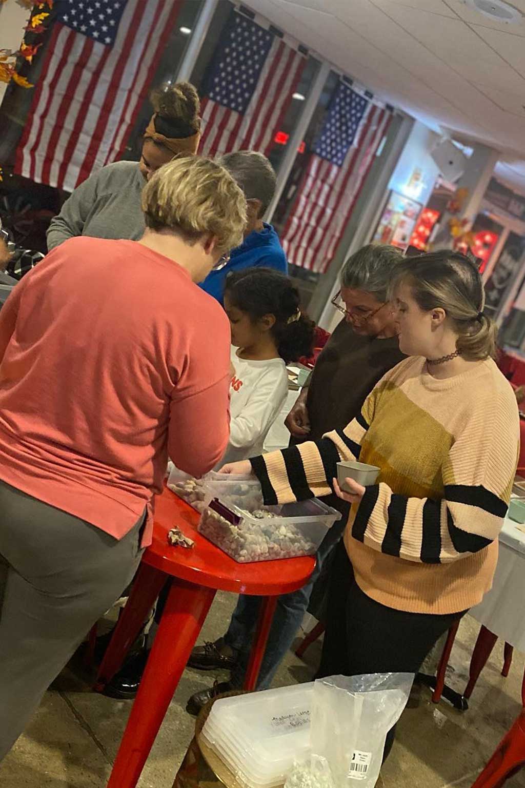 People gathered around a table with American flags in the background